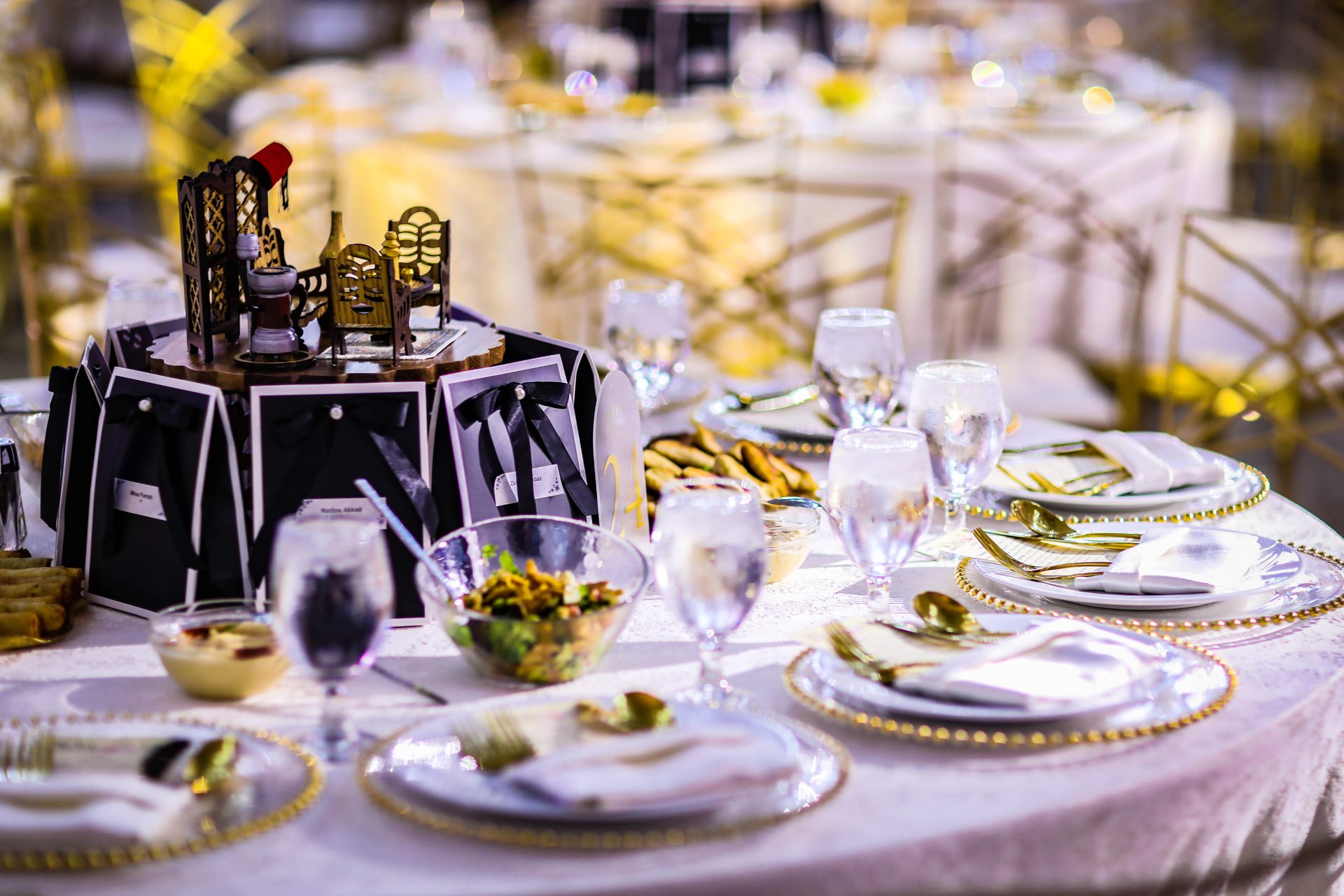 Reception table with gold-rim chargers, mezze bowls and a carved centerpiece