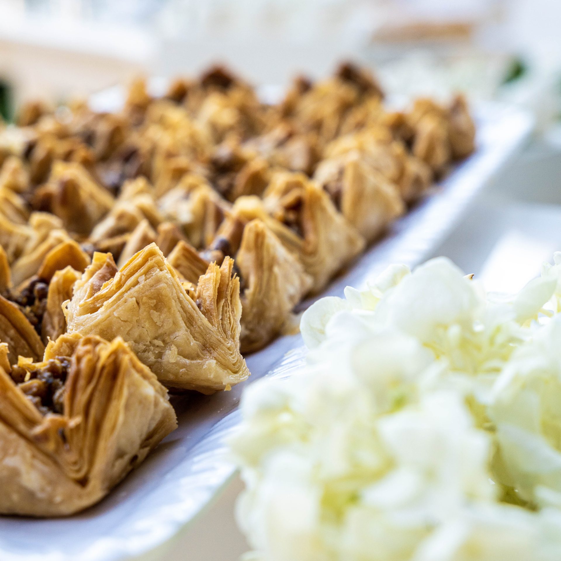 Rolled baklava pastries plated with white florals
