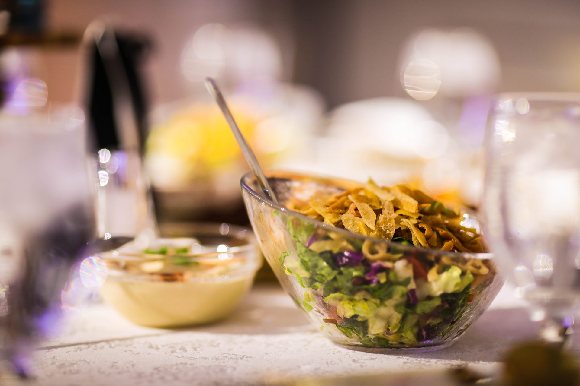 Fattoush salad in a glass bowl with labneh, warm candlelight behind